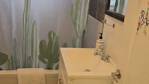A bathroom with a bathtub, a sink, and a mirror.