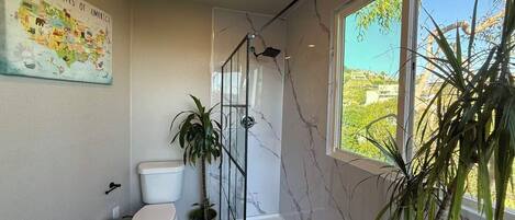 A bathroom with a toilet, a shower, and a large window.