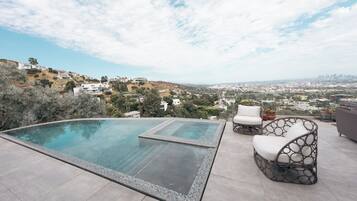 Una piscina infinita en la azotea con una vista despejada del paisaje urbano.
