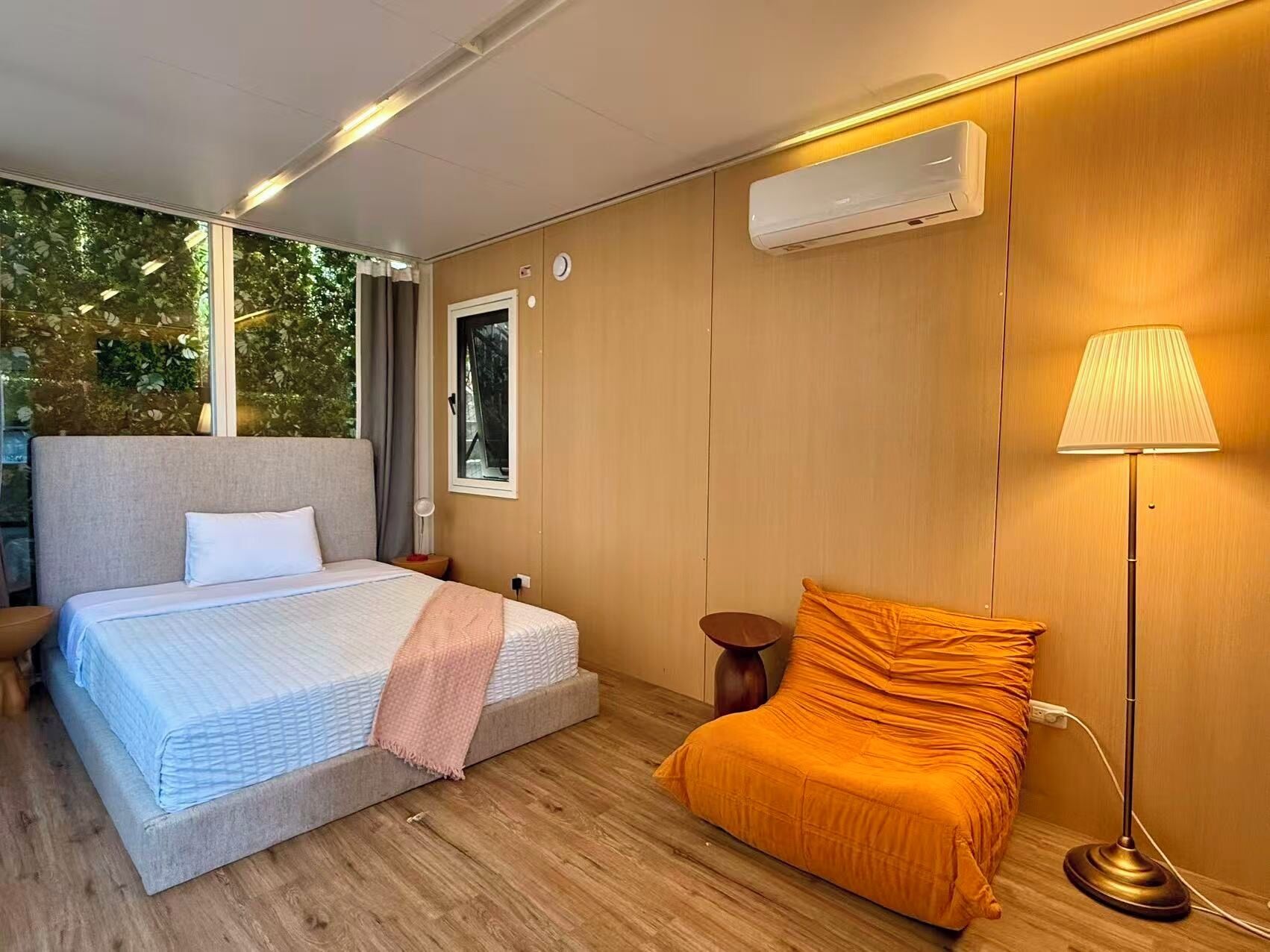 Een slaapkamer met een bed, nachtkastje, lamp en een airconditioning.