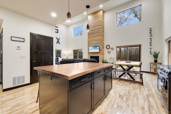 A modern kitchen with a central island, built-in appliances, and a dining area with a wooden table and chairs.