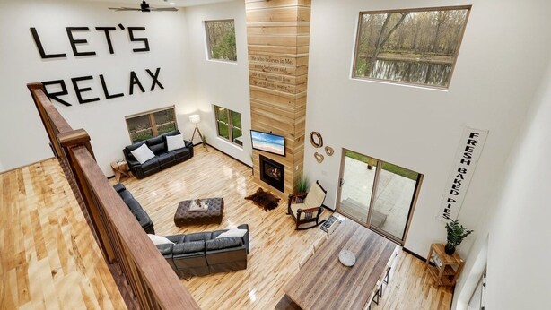 A spacious living room with a fireplace, a large window, and a ceiling fan.