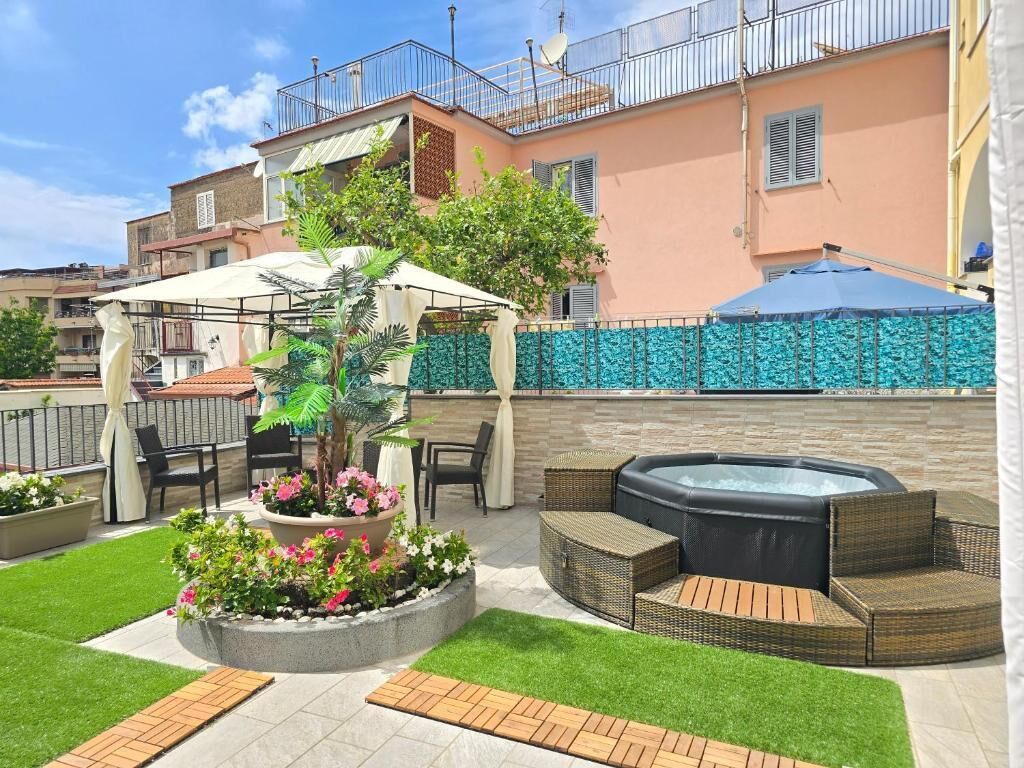 A patio area with a hot tub, outdoor seating, and a garden with flowers.