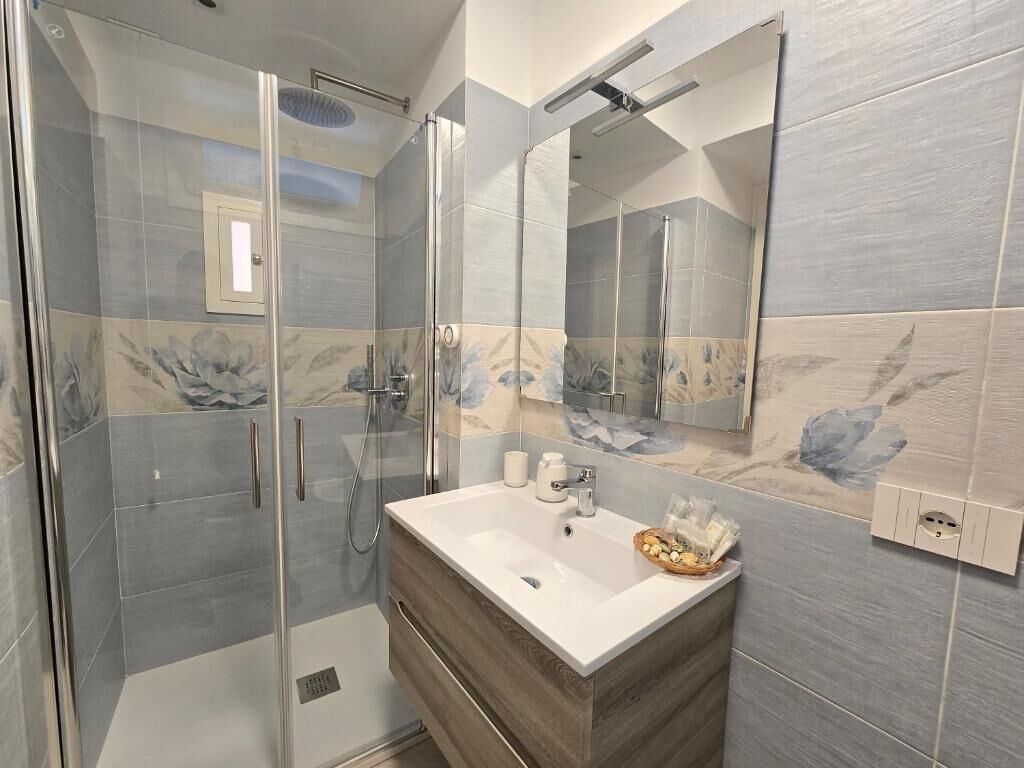 A modern bathroom with a glass-enclosed shower, a vanity with a sink, and a large mirror.