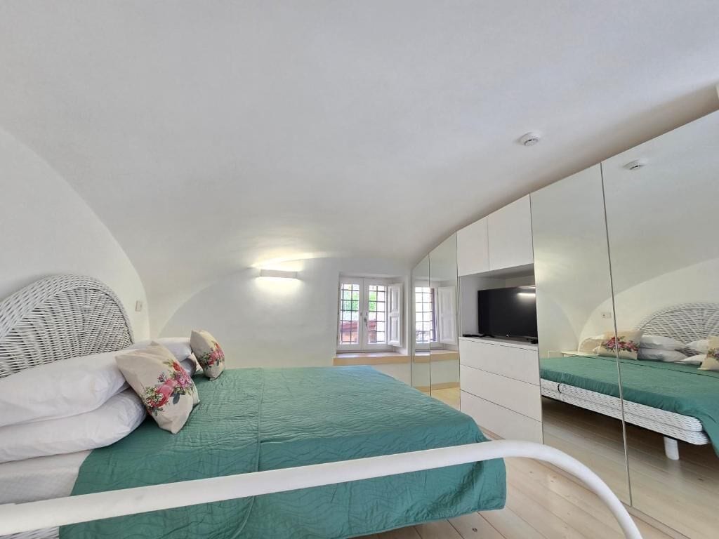 A bedroom with a bed, a TV, a wardrobe, and a mirror.