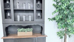 A dark grey, vintage-style cabinet with multiple shelves and a wooden countertop.