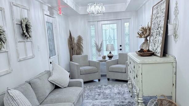 A spacious living room with a grey sofa, two armchairs, a coffee table, and a decorative rug.