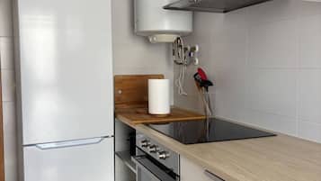 Una cucina moderna con frigorifero bianco, forno a incasso, piano cottura e un piano di lavoro in legno.