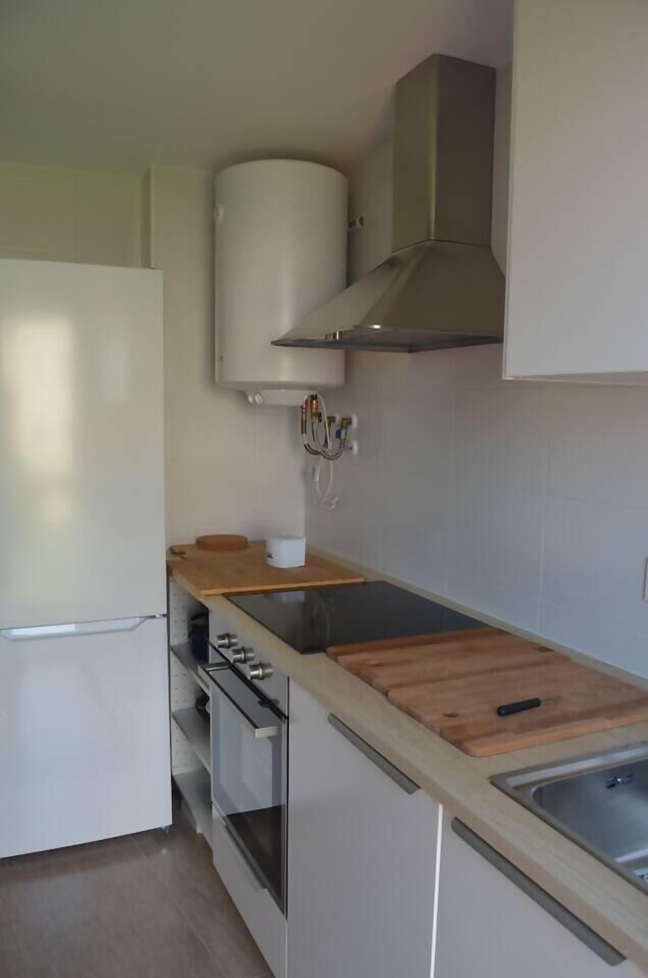 A modern kitchen with a built-in oven, a stainless steel sink, and a wooden countertop.