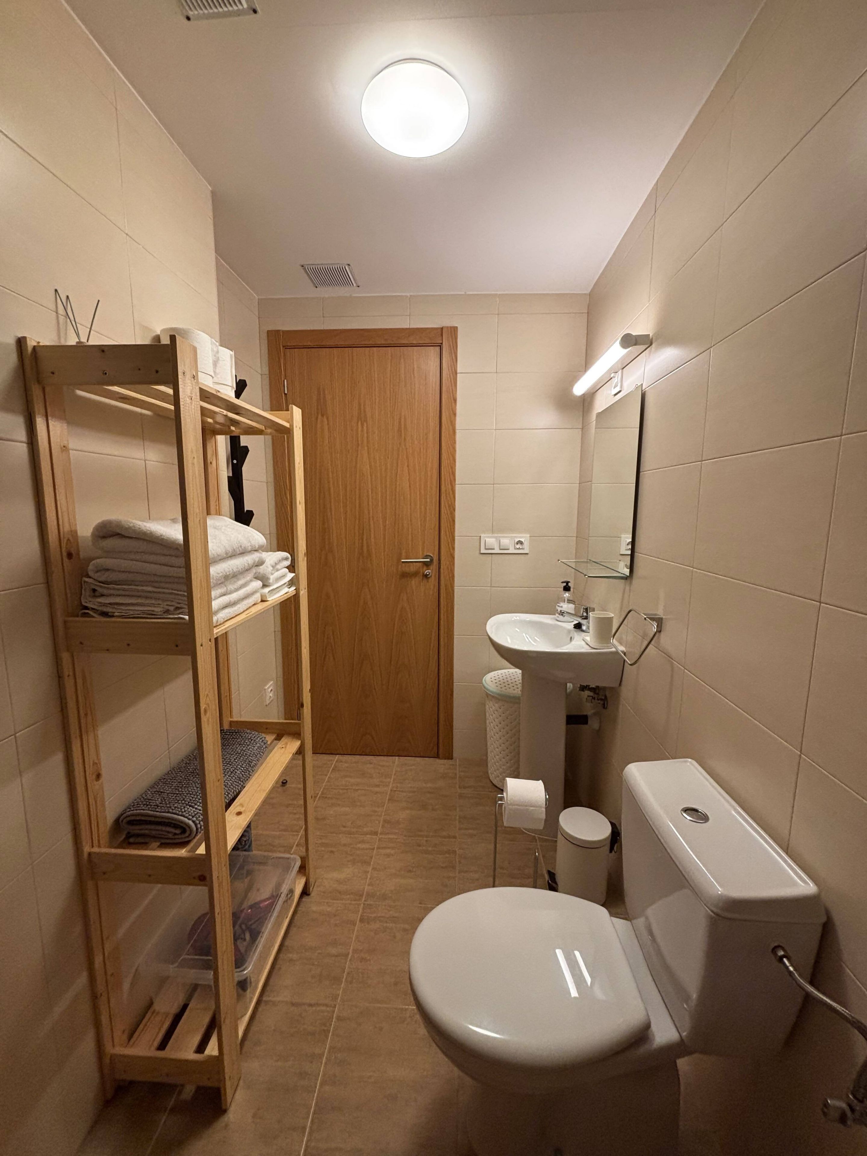 Ein kleines Badezimmer mit einer Holzkonsolen, einer Toilette, einem Waschbecken und einem Spiegel.