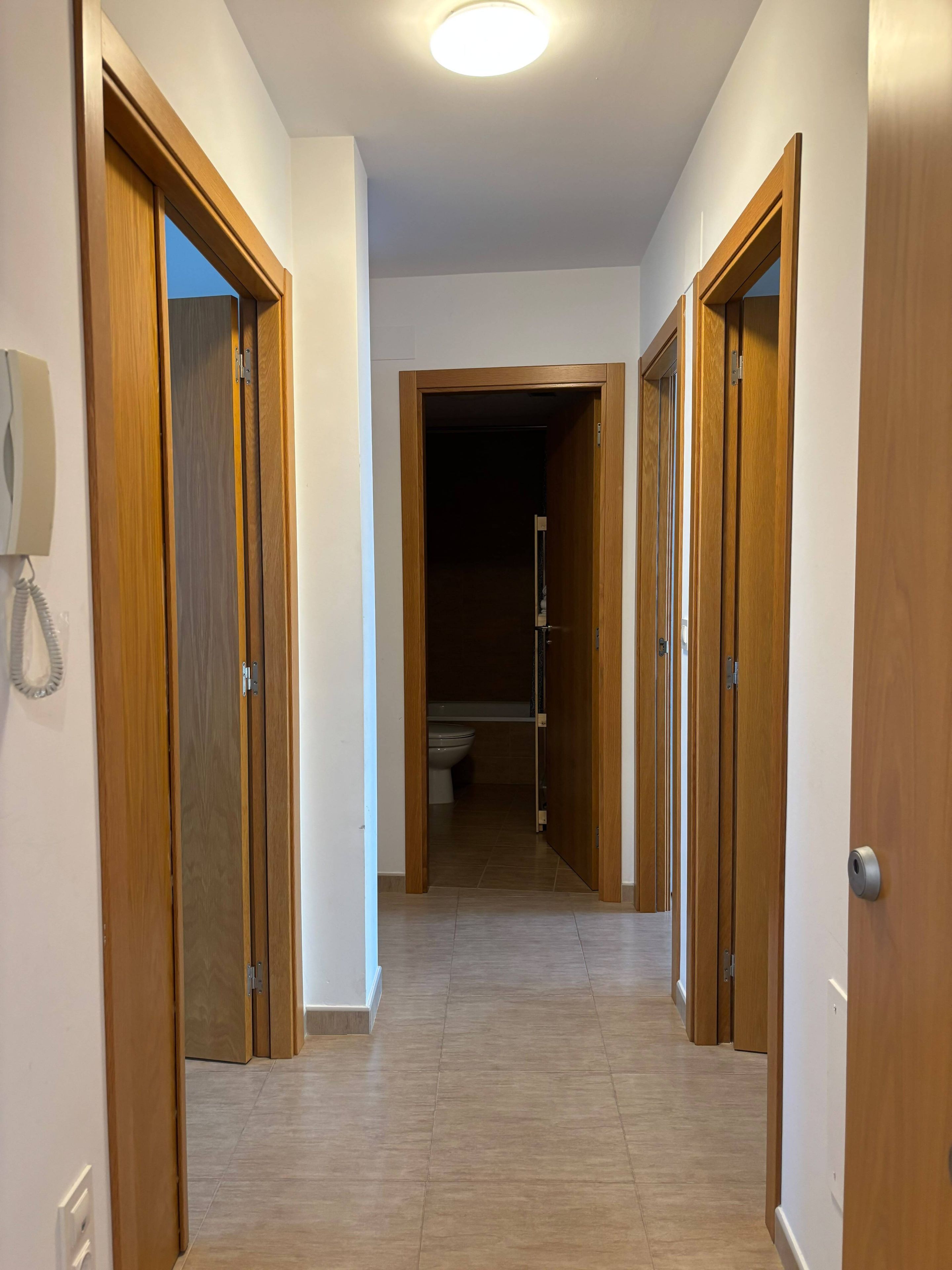 Un pasillo con puertas de madera que dan a un baño.