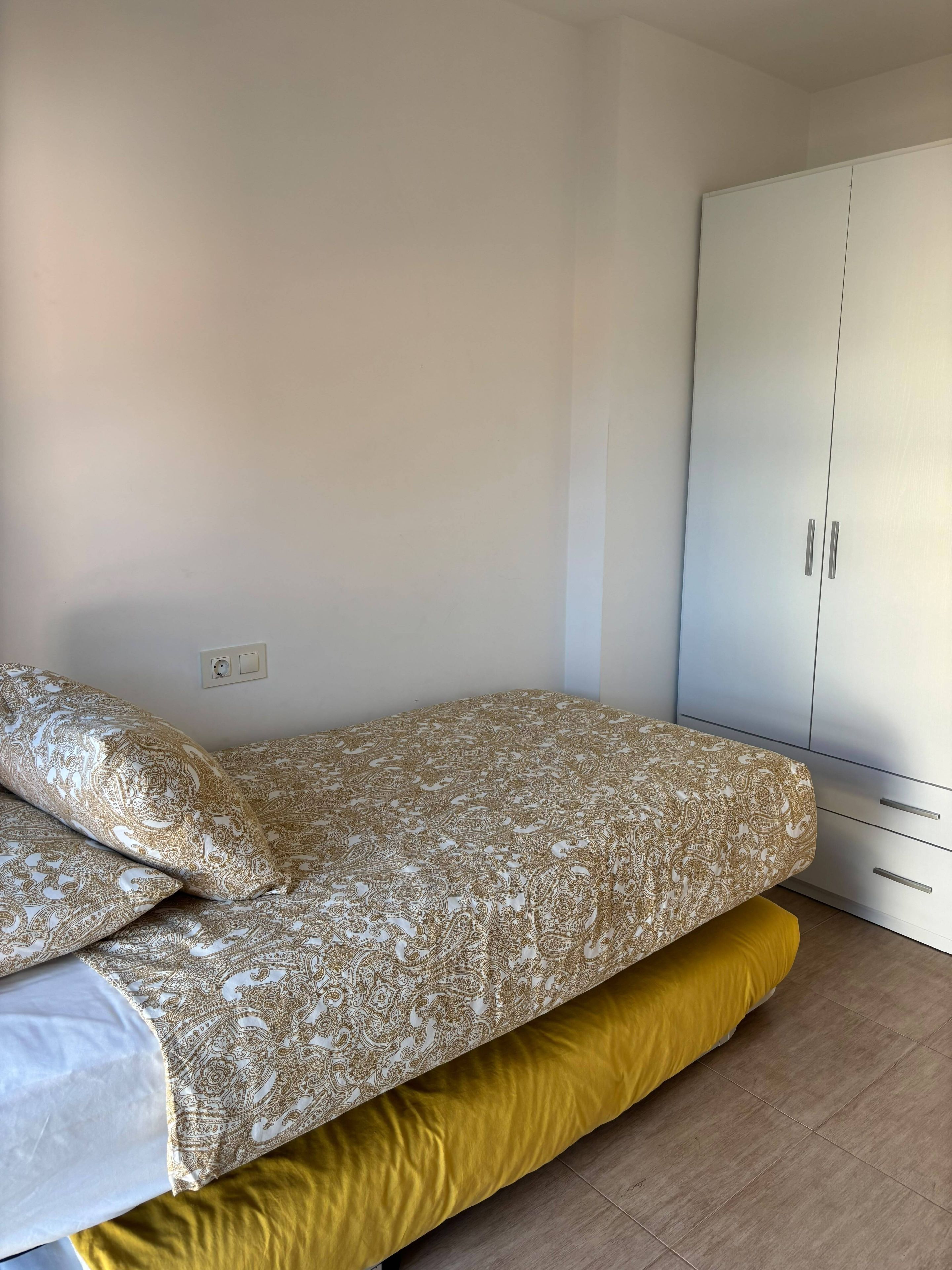 Ein Schlafzimmer mit einem Bett, einem Kleiderschrank und einer Steckdose.