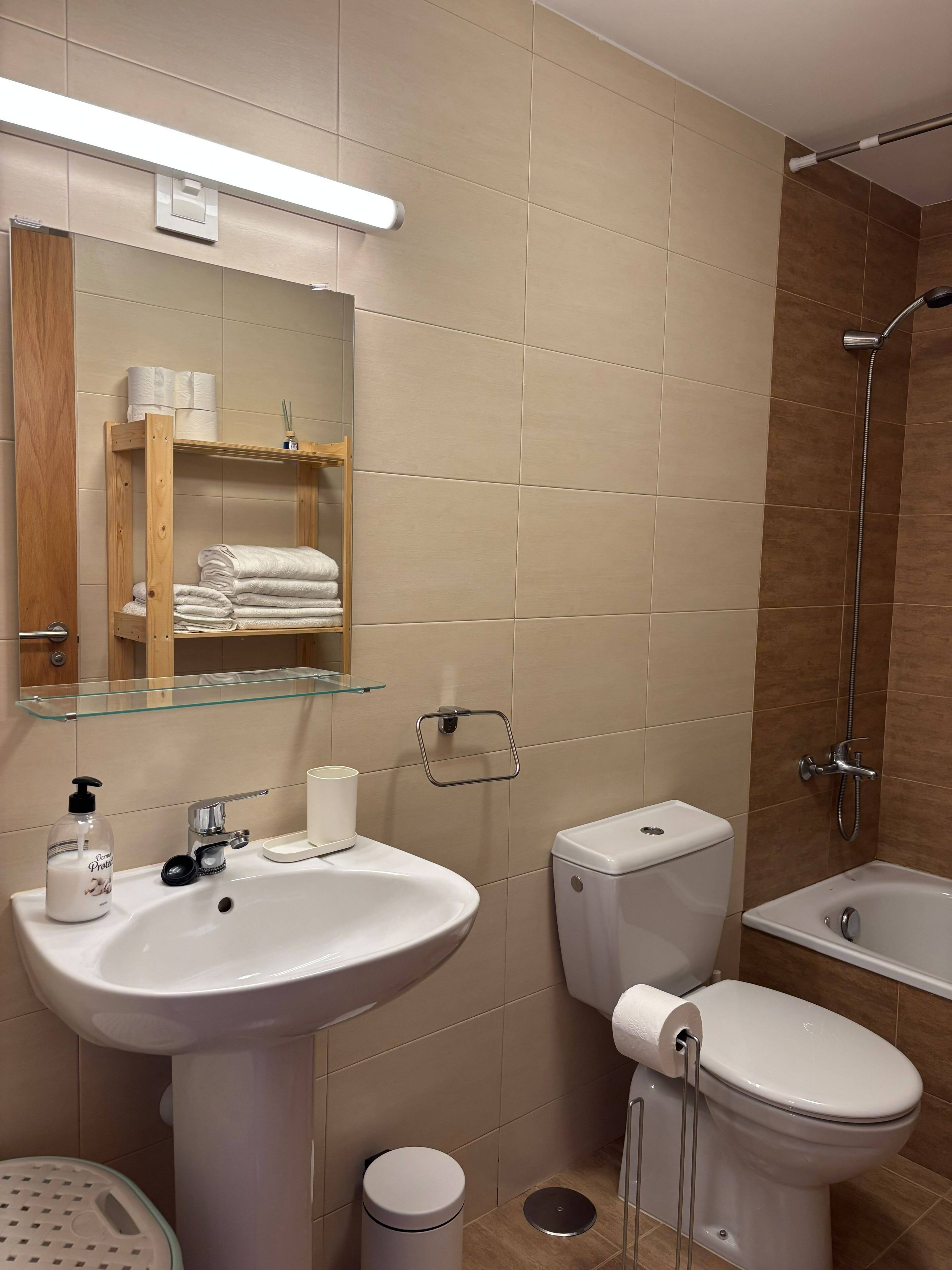 Un baño moderno con lavamanos, inodoro y ducha.