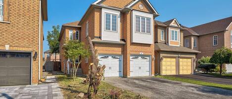 A two-story residential house with a brick facade, white trim, and a garage with two doors.