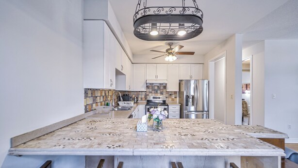 A modern kitchen with a large island, stainless steel appliances, and a decorative ceiling fan. - Family frieindly house in richmond hill 7beds (Richmond Hill)