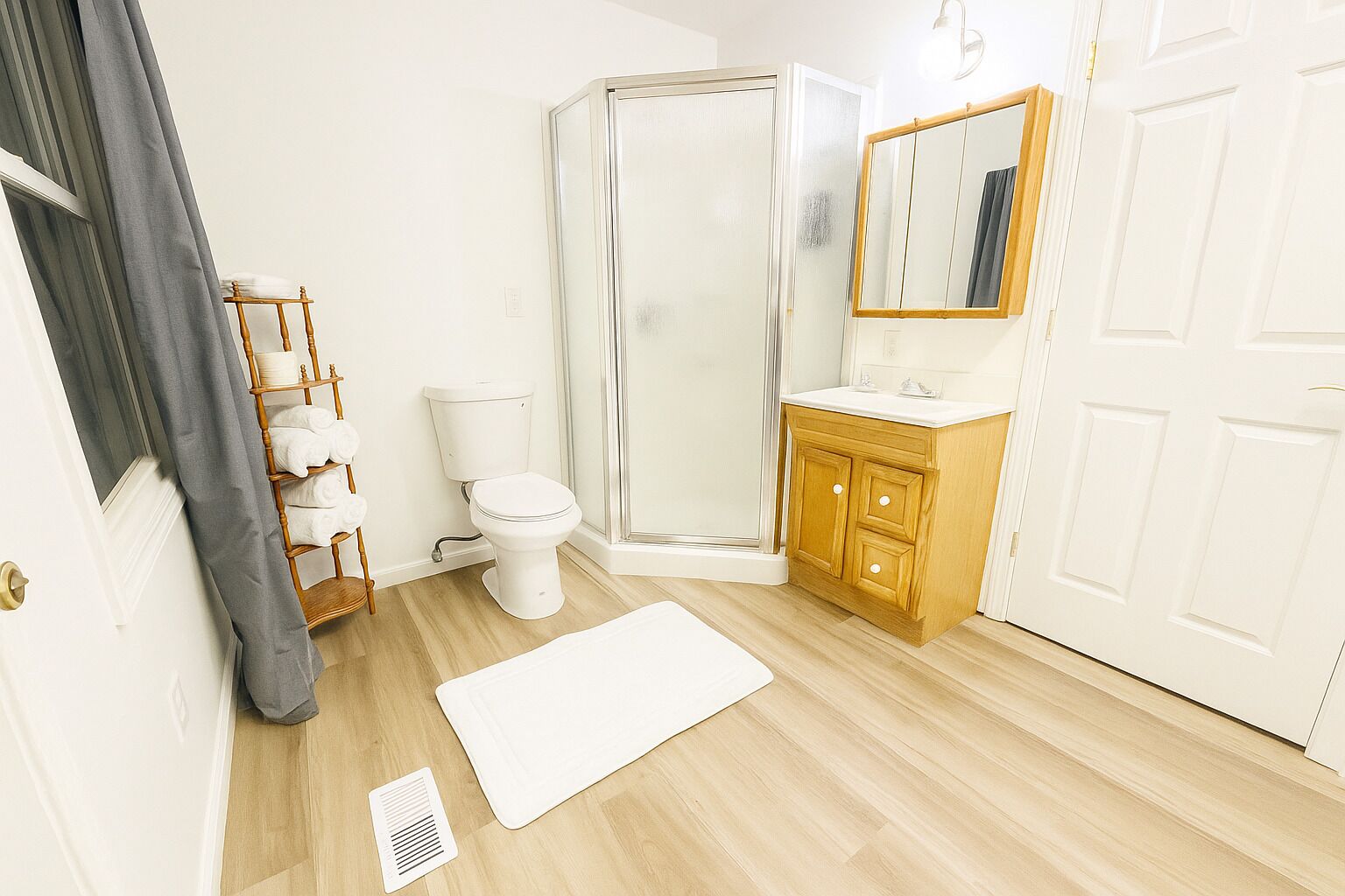 Et badeværelse med toilet, bruser, vaskebord og spejl.