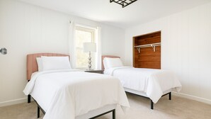 A bedroom with two beds, a window with curtains, a bedside lamp, and a wooden wardrobe. - Spacious Family Retreat  2 Indoor Fireplaces + Volleyball Fun! (Flat Rock)