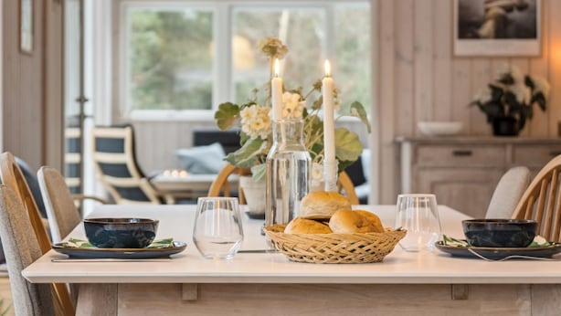 Mesa de jantar com velas, um vaso de flores e pão.