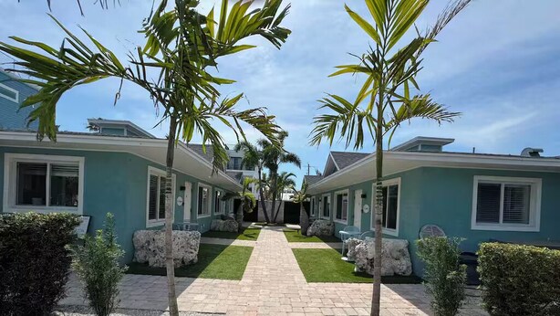A pathway leading to a row of two-story buildings with a central lawn. - "St.Thomas"-Family Villa-2 Blks 2 Beach-BeachGear-2 BR 2 BA-Tranquil Courtyard (Bradenton Beach)