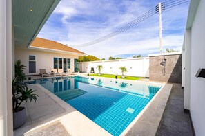 A modern outdoor swimming pool with a clear blue tile design, surrounded by a white wall and a tiled deck. - Modern Villa 3BR - Great Location KL3 (Hua Hin)