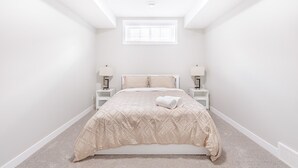 A bedroom with a bed centered under a skylight, flanked by nightstands with lamps. - Charming 2Bed Retreat near Airport & Banff w/ desk (Airdrie)