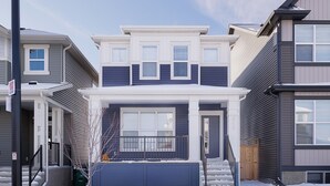A two-story house with a front porch, a garage, and a snow-covered driveway. - Charming 2Bed Retreat near Airport & Banff w/ desk (Airdrie)