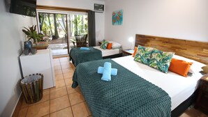 A hotel room with two beds, a TV, a small fridge, and a view of the outdoors. - Rainforest Motel (Mission Beach)