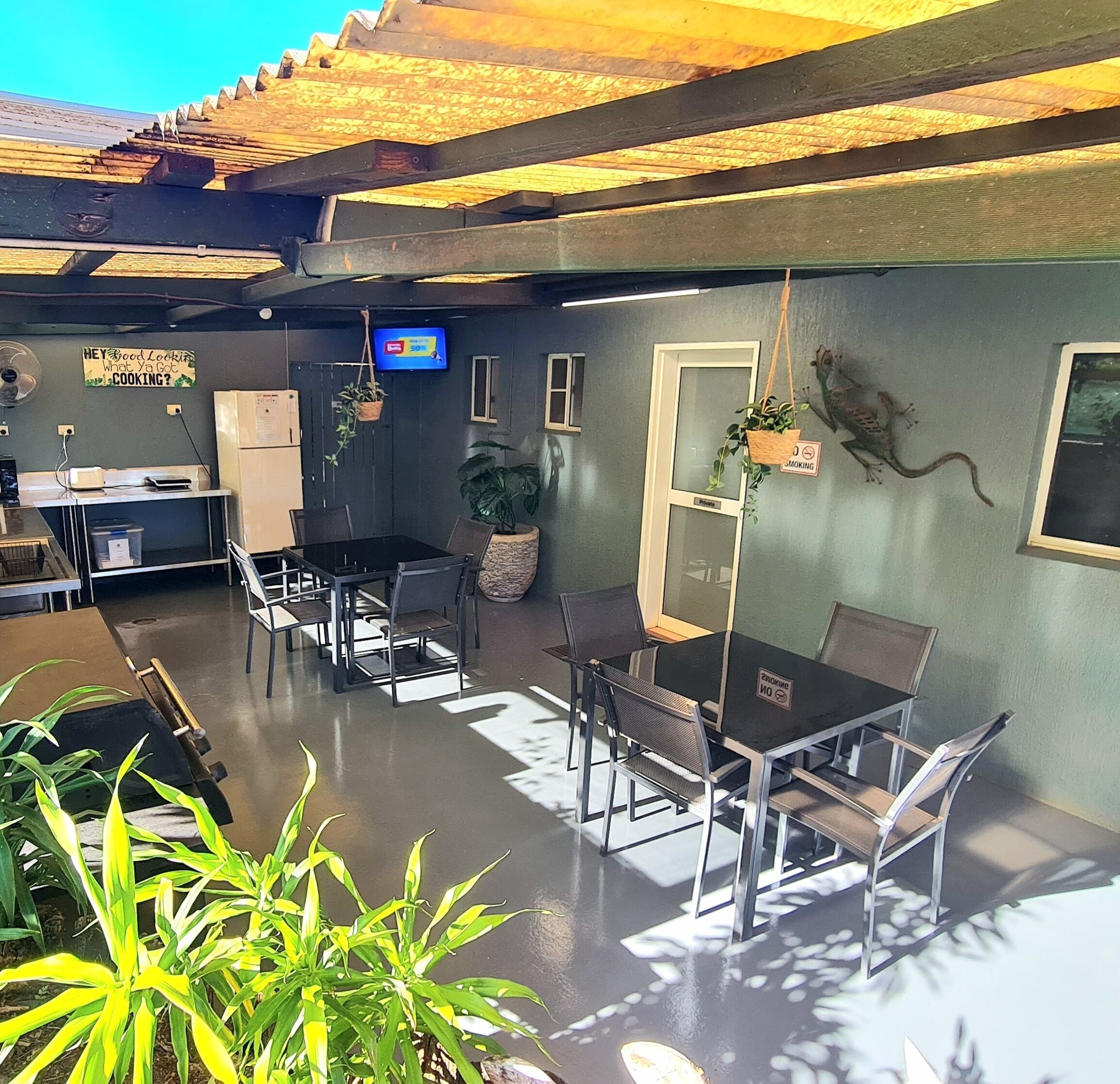 Un restaurante con mostrador, mesas, sillas y plantas colgantes.