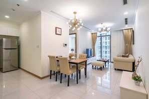 A modern kitchen with a built-in refrigerator, a dining area with a wooden table and chairs, and a living room with a sofa and a coffee table. - Chip Stay (Ho Chi Minh City)