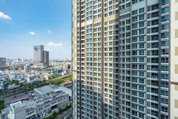 A high-rise building with a grid of windows and balconies, surrounded by a cityscape with other buildings and a clear sky. - Chip Stay (Ho Chi Minh City)
