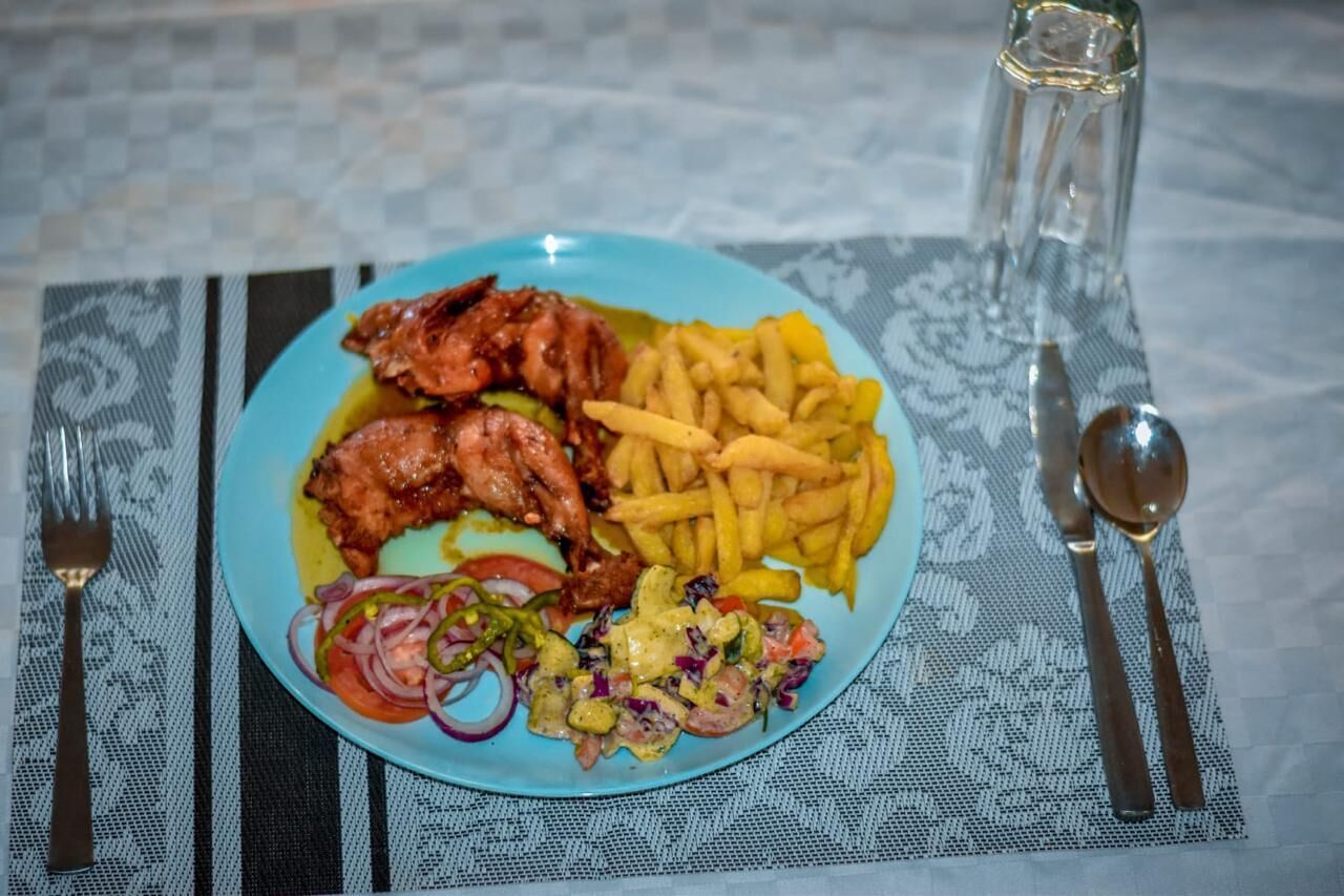Ein Teller mit gebratenem Hähnchen, Pommes und einem Salat auf blauem Geschirr.