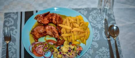 Ein Teller mit gebratenem Hähnchen, Pommes und einem Salat auf blauem Geschirr.