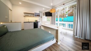 A modern bedroom with a bed, a desk, a TV, and a balcony with curtains. - Stay Studio Villa Hideaway (Ho Chi Minh City)