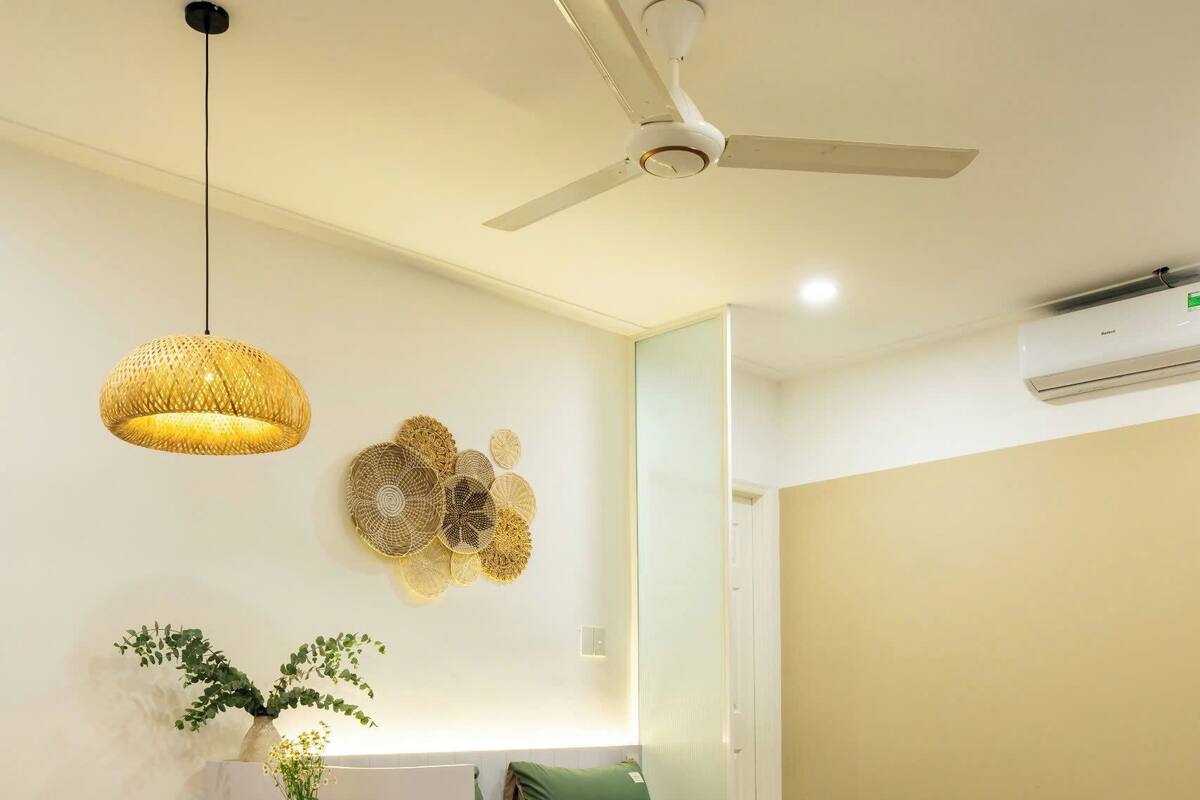 Un dormitorio moderno con cama, una mesa de comedor con sillas, un ventilador de techo y un adorno en la pared.