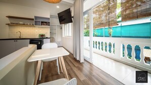 A modern kitchen with a flat-screen TV, white cabinets, and a dining area with a white table and chairs. - Stay Studio Villa Hideaway (Ho Chi Minh City)