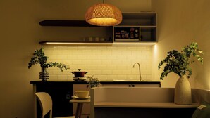 A modern kitchen with white subway tiles, a hanging woven light fixture, and two potted plants. - Stay Studio Villa Hideaway (Ho Chi Minh City)