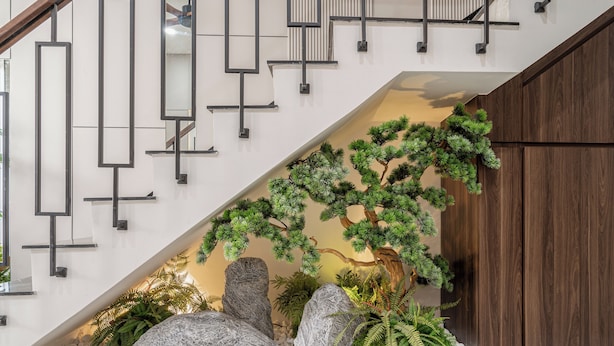 A modern staircase with geometric wall designs, a wooden door, and a decorative indoor garden with rocks and greenery. - Luxury Apartment Manhattan Grand Park By An Gia Hospitality (Ho Chi Minh City)