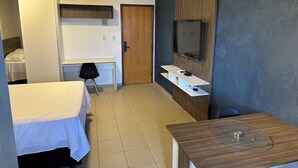 Una habitación de hotel con una cama, un escritorio, una silla, un televisor y una mesita.