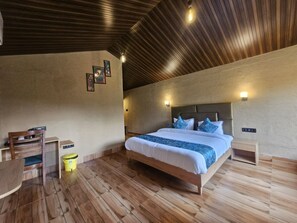 A bedroom with a wooden bed, bedside tables, a desk, and a chair. - Nayana Corbett Resort (Belparao)