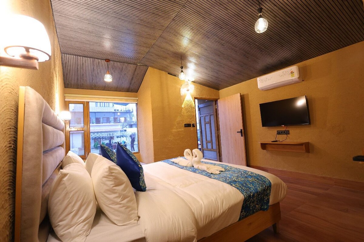 Een hotelkamer met een bed, een aan de muur bevestigde televisie en een airconditioning.