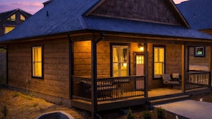 Une maison de style chalet en rondins de bois, dotée d’un porche, d’un hall d’entrée couvert et d’un petit jardin à l’avant.