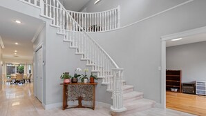 A modern staircase with white balusters and a wooden console table with potted plants. - VANCOUVER WEST BEAUTIFUL HOUSE (Vancouver)