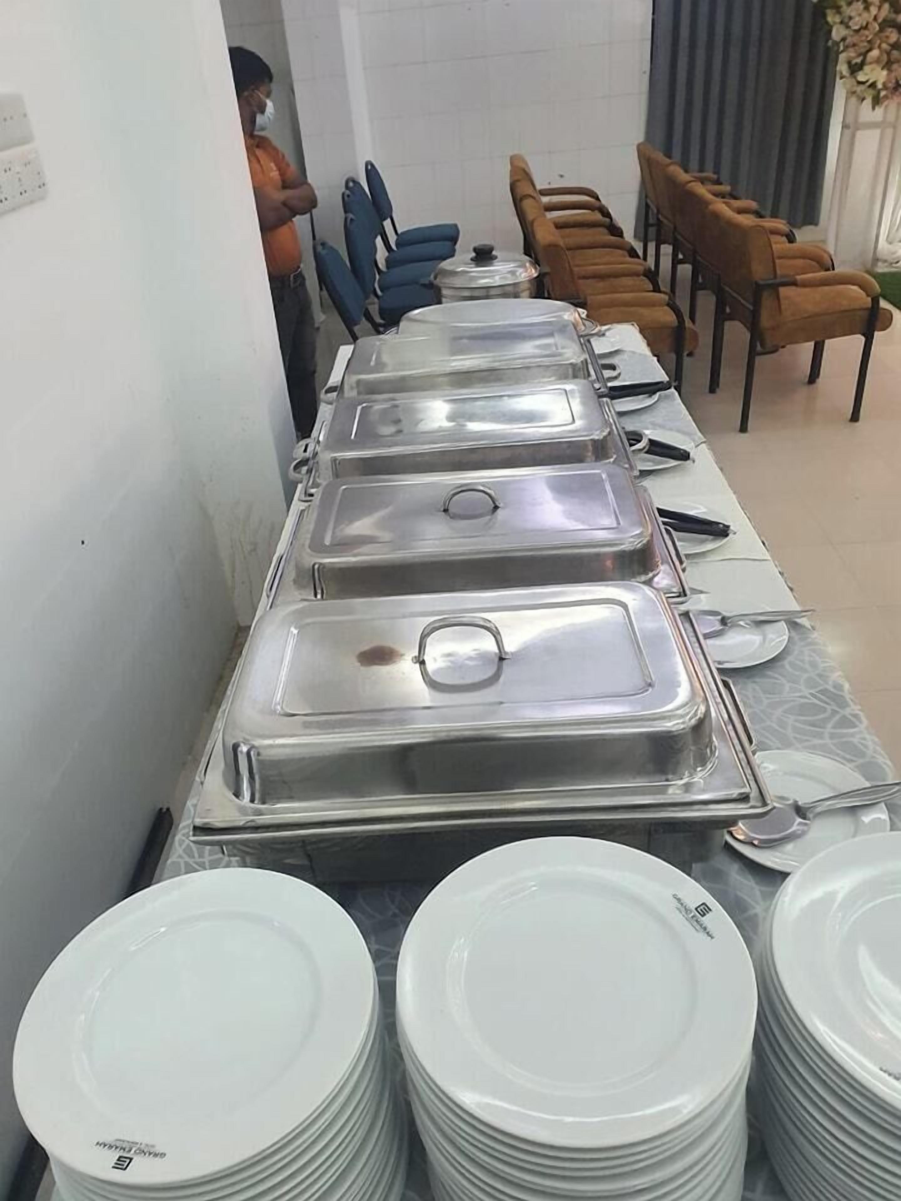 A buffet setup with multiple serving stations and stacked white plates.