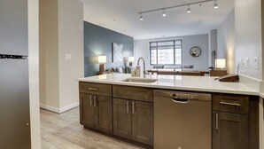 A modern kitchen with a central island, built-in appliances, and a large window providing natural light. - Sojourn | Courtland Towers w/ Entertainment Area (Arlington)