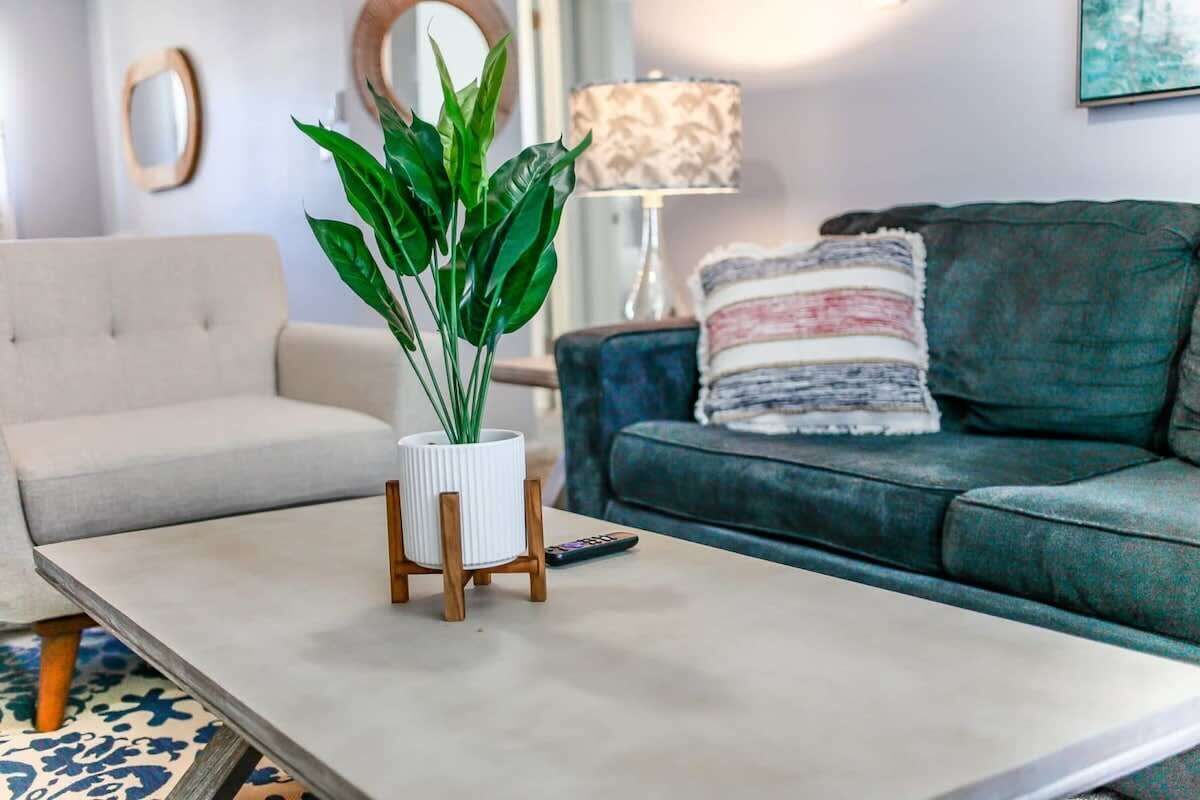 A living room with a sofa, a coffee table with a plant, and a lamp.
