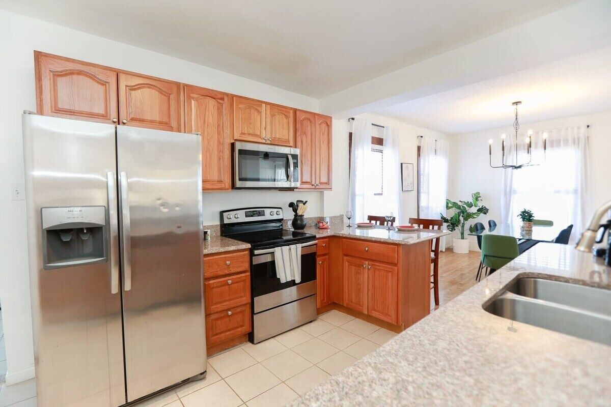 A modern kitchen with wooden cabinets, stainless steel appliances, and a granite countertop.