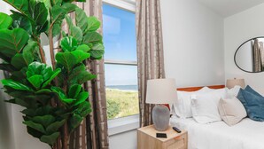 Une chambre d’hôtel avec un lit, une table de chevet, une lampe et une vue sur l’extérieur.