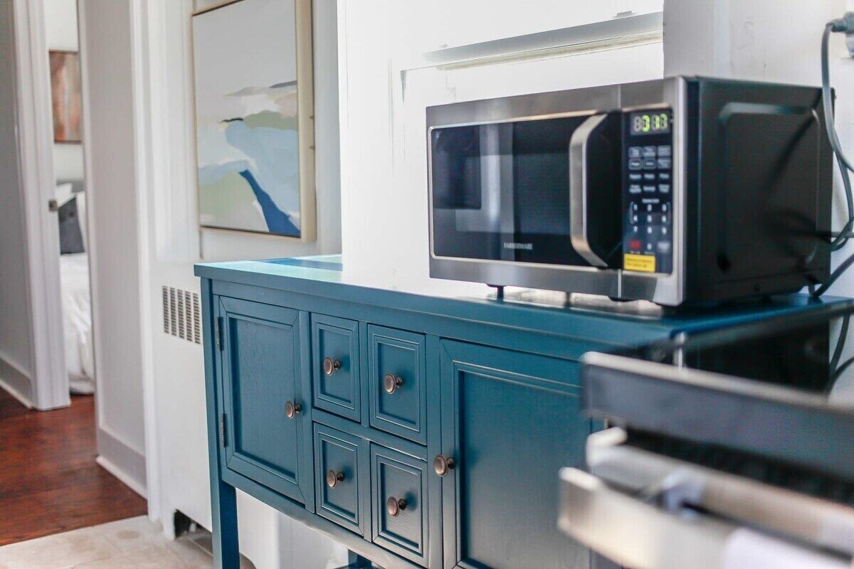 Une cuisine avec un meuble de couleur turquoise et un four à micro-ondes posé sur le dessus.