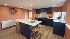Cozinha moderna com ilha central, banquetas de madeira e forno embutido.