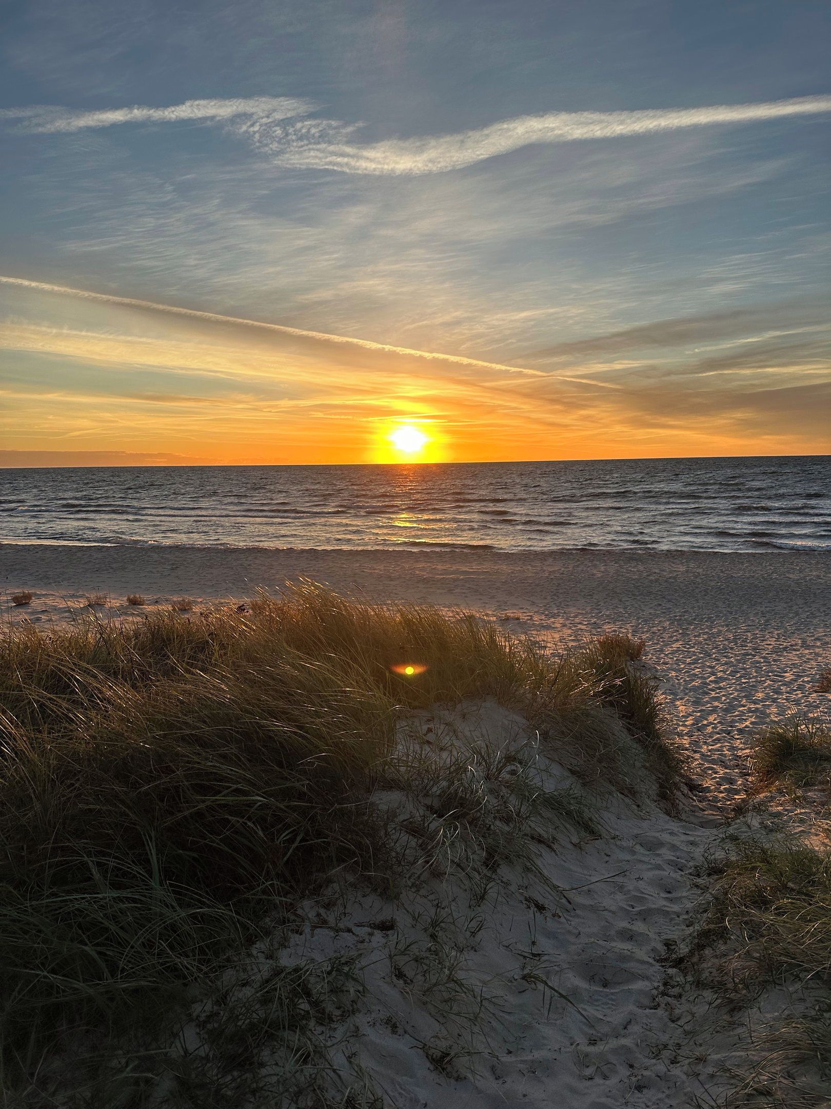 A beach with sand dunes and the ocean.